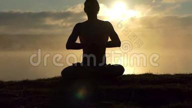 闪亮的人坐在湖岸上，在日落时缓慢地祈祷和练习瑜伽。